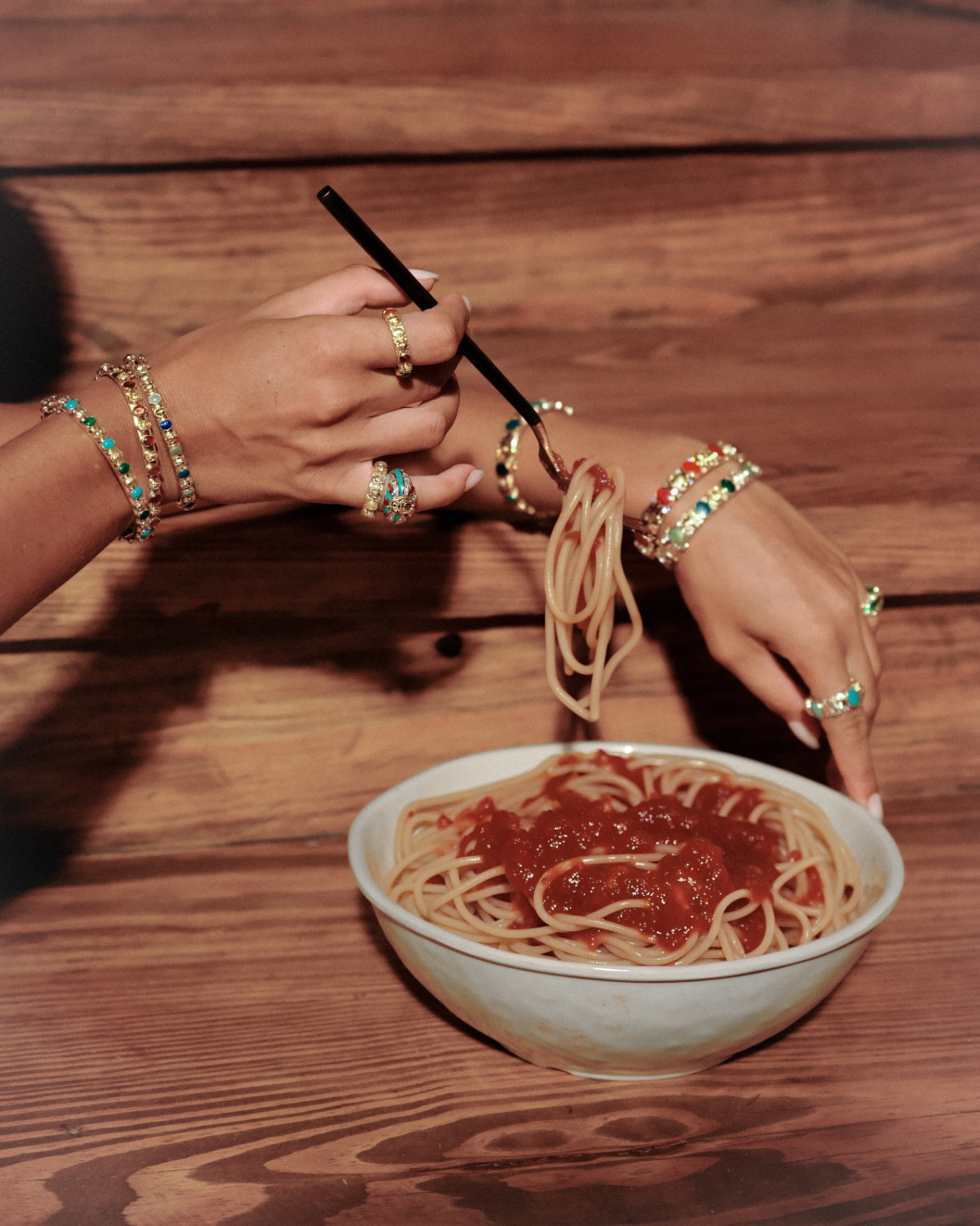 Hands in stacked bangles twirling spaghetti