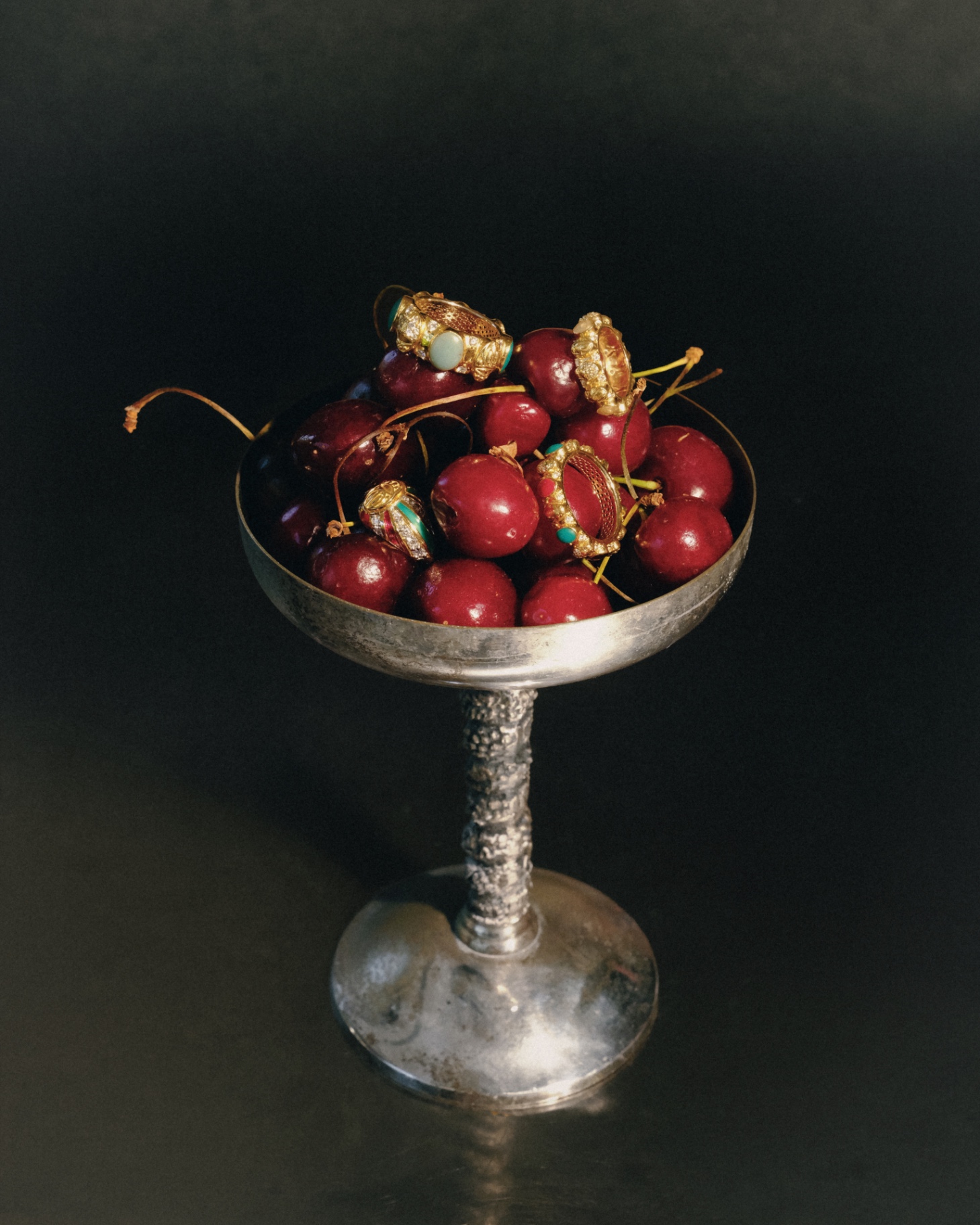 Gold rings on cherries in a silver coupe